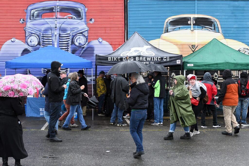 popup tents are visited by people in rain gear outside the California Auto Museum